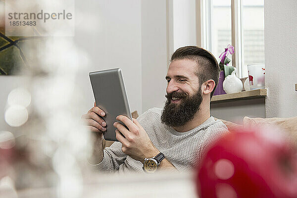Junger Mann lächelt und benutzt ein digitales Tablet