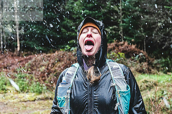 Frau mit offenem Mund fängt Schneeflocken auf der Zunge