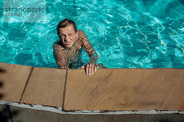 Teenager-Junge spielt an sonnigem Tag im Pool