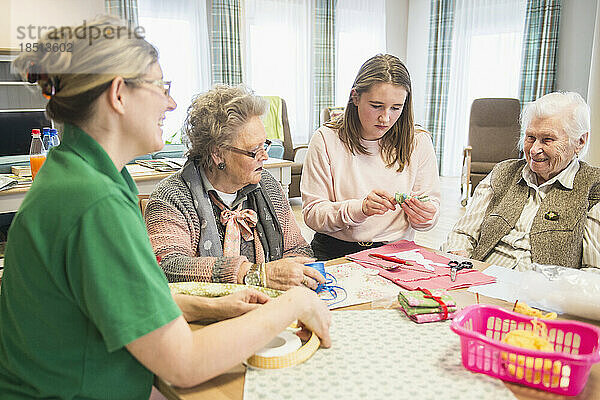 Ältere Frauen mit Mädchen und Krankenschwester machen handwerkliche Aktivitäten im Erholungsheim