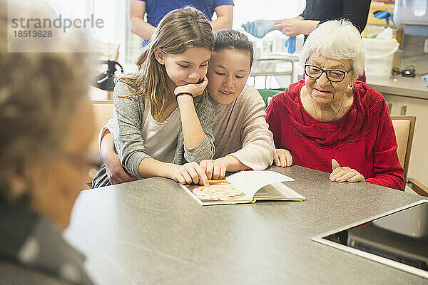 Ältere Frauen mit Mädchen lesen Buch im Altersheim