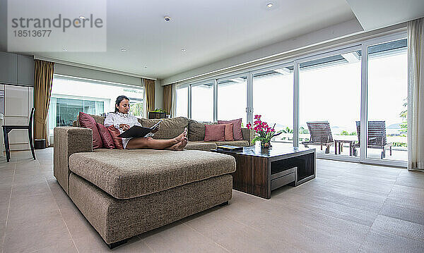 Frau entspannt sich auf Sofa in Ferienwohnung in Phuket