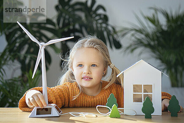 Nettes Mädchen  das zu Hause ein Windturbinenmodell betreibt