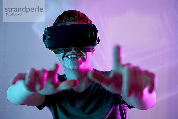 Glücklicher junger Mann  der zu Hause Spiele durch eine VR-Brille spielt