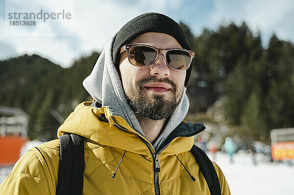 Lächelnder Mann mit Sonnenbrille im Skigebiet