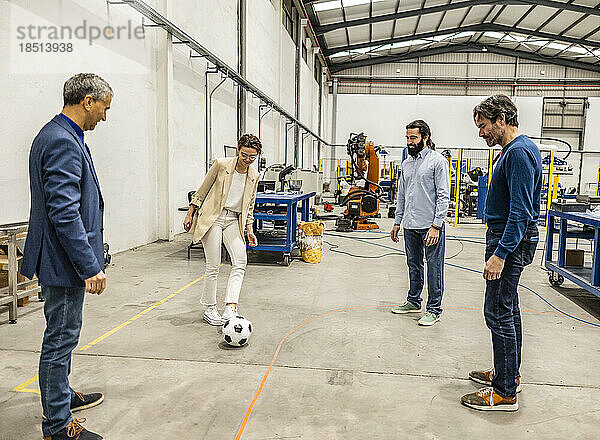 Geschäftskollegen spielen in der Fabrik mit Fußball