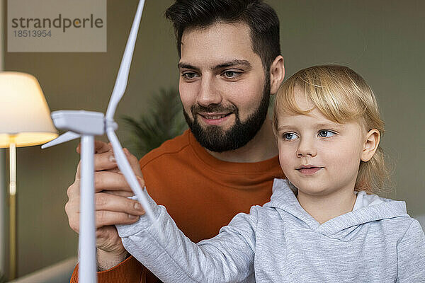 Lächelnder Vater unterrichtet Sohn zu Hause über Windkraftanlagen