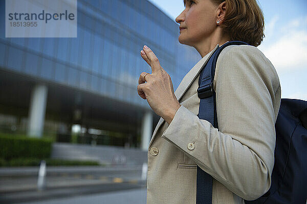 Geschäftsfrau mit Rucksack steht mit gekreuzten Fingern
