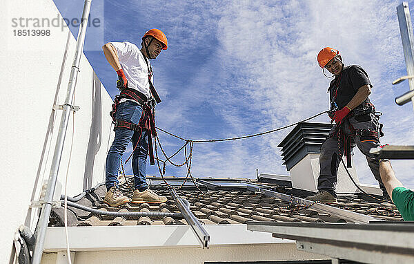 Techniker mit Sicherheitsgurt stehen auf dem Dach