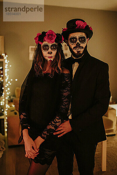 Paar in Kostümen zum Tag der Toten steht zu Hause