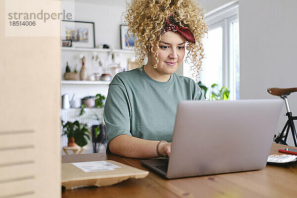 Lächelnde Geschäftsfrau  die am Schreibtisch am Laptop arbeitet