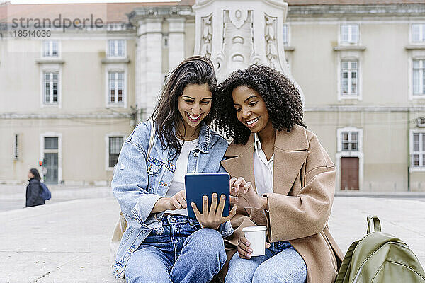 Lächelnde junge Freunde  die einen Tablet-PC nutzen