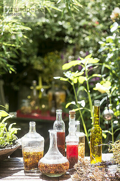 Frische Glasflaschen mit Öl und Essig am Tisch im Garten