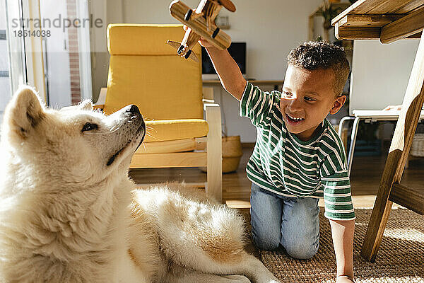 Netter Junge  der zu Hause mit Hund spielt