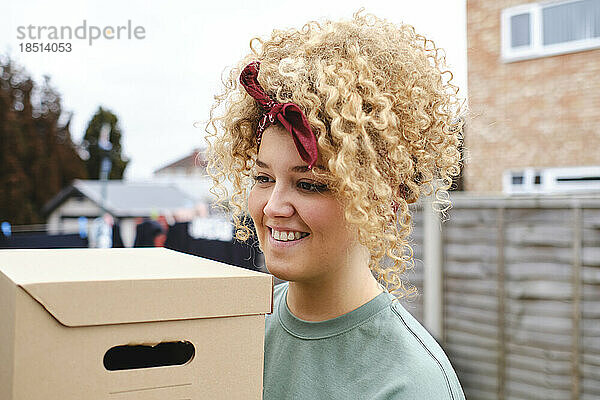 Lächelnde junge Frau mit Karton