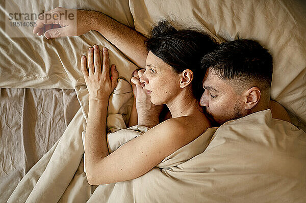Man and woman snuggling in bed at home