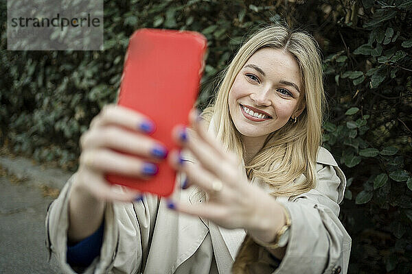 Glückliche Frau macht Selfie mit dem Handy in der Nähe von Pflanzen