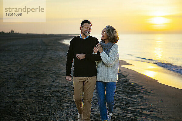 Glückliches älteres Paar  das am Strand spaziert