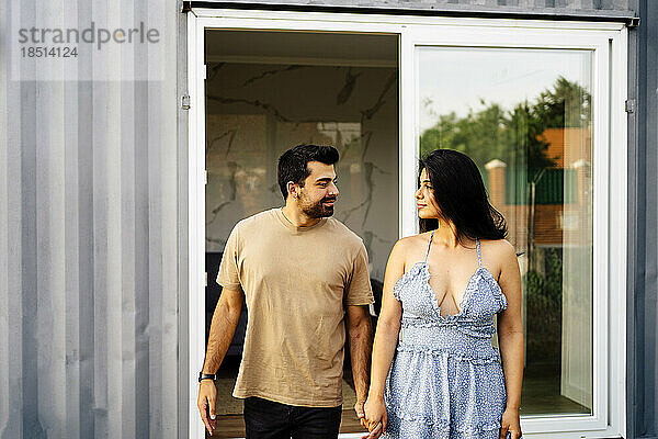 Romantisches Paar hält Händchen vor Containerhaus