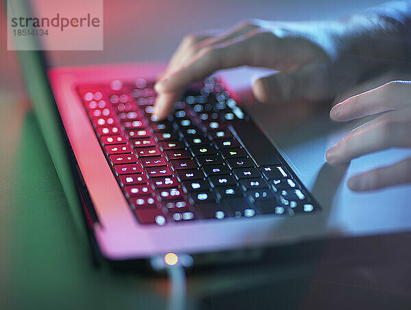 Hacker arbeitet im Büro an beleuchtetem Laptop