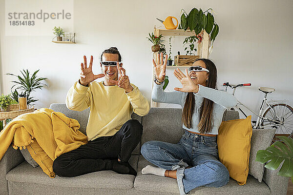Glückliches Paar mit Smart-Brille gestikuliert zu Hause