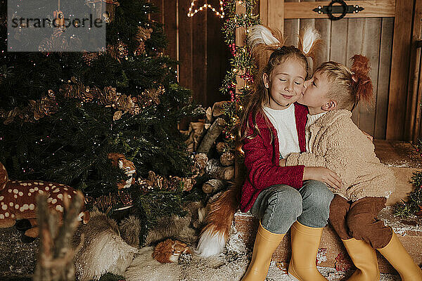 Brother kissing sister's cheek at Christmas