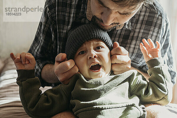 Vater trägt Strickmütze für Sohn zu Hause