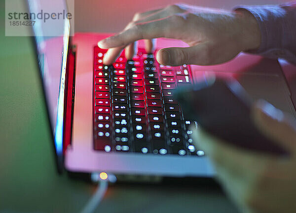 Hände tippen im Dunkeln im Büro auf der Laptoptastatur