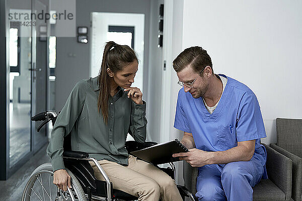 Arzt bespricht sich mit Patient im Rollstuhl