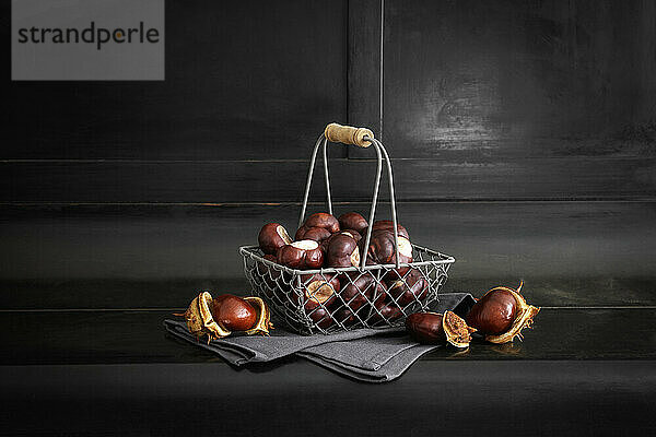 Chestnuts in wire basket standing against black background