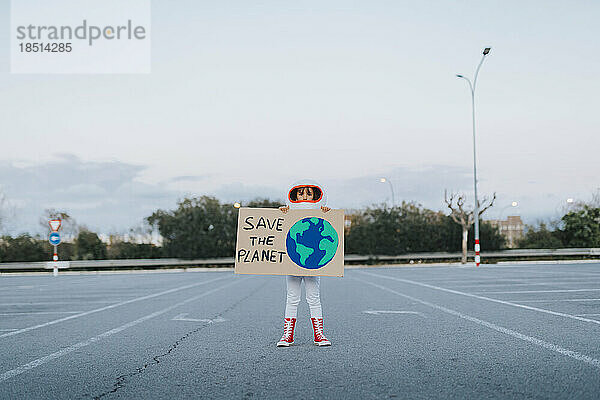 Ein als Astronautin verkleidetes Mädchen zeigt „Save The Planet“-Ausschnitt auf dem Parkplatz
