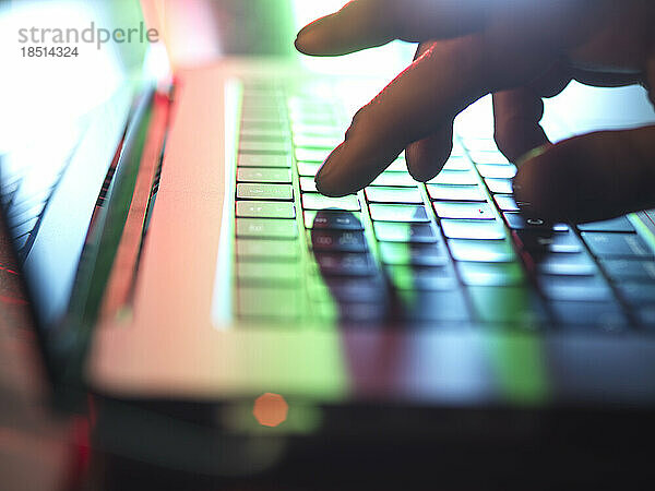 Hände tippen im Dunkeln im Heimbüro auf der Laptop-Tastatur
