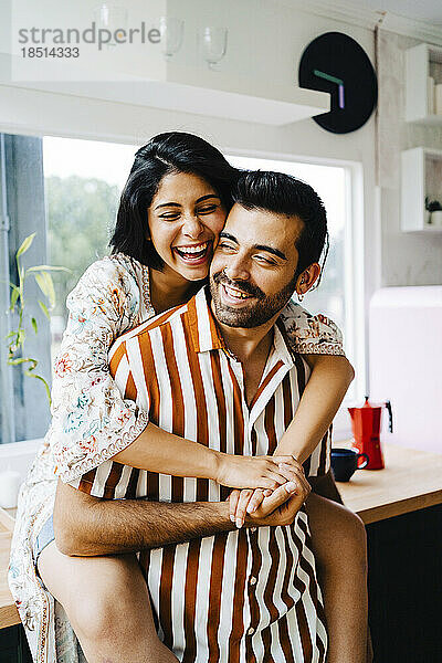 Happy woman embracing boyfriend in kitchen at home