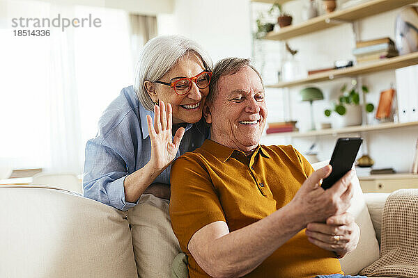 Glückliches älteres Paar bei einem Videoanruf über das Smartphone zu Hause