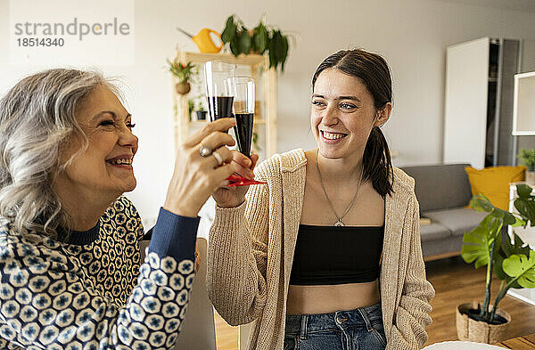 Glückliche Mutter und Tochter  die zu Hause Weingläser anstoßen