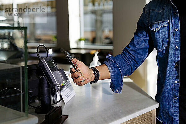 Mann bezahlt per Smartphone im Café