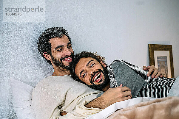 Glückliches schwules Paar  das sich zu Hause gemeinsam im Bett entspannt