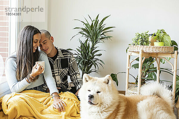 Affectionate couple having coffee with dog in foreground