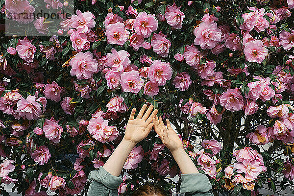 Frau mit erhobenen Armen vor Blumen