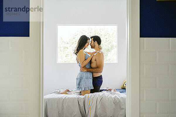 Affectionate couple kneeling on bed at home