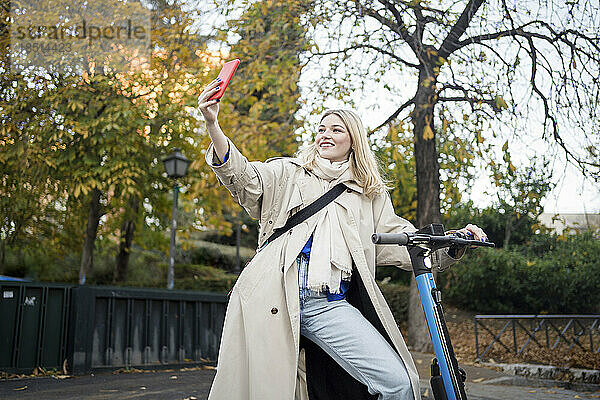 Frau macht Selfie mit Elektroroller