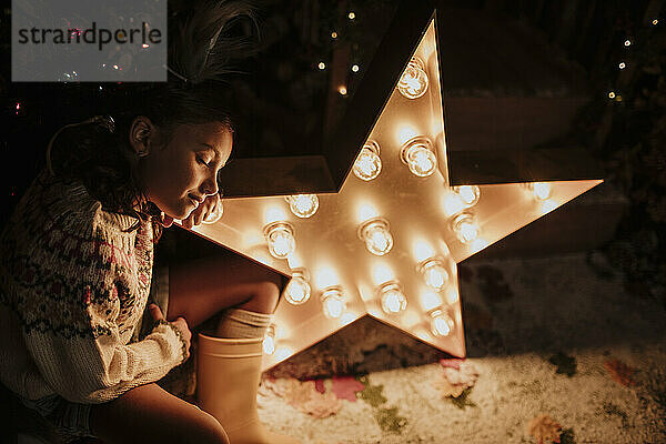 Girl with eyes closed leaning head on star shape light