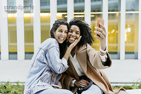 Glückliche Freunde  die vor dem Gebäude ein Selfie mit dem Smartphone machen