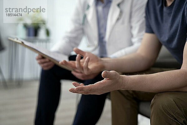 Mann gestikuliert und diskutiert mit Arzt in der Klinik