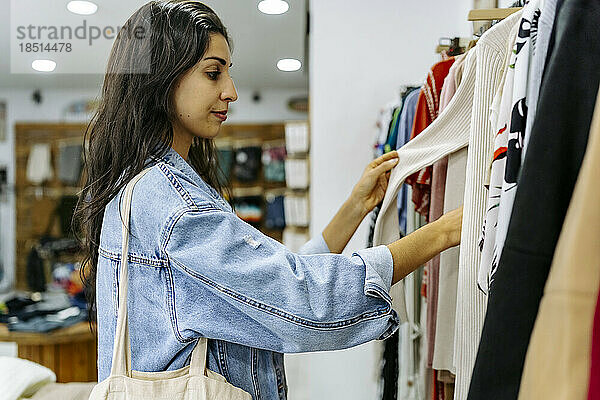 Young woman choosing clothes at store