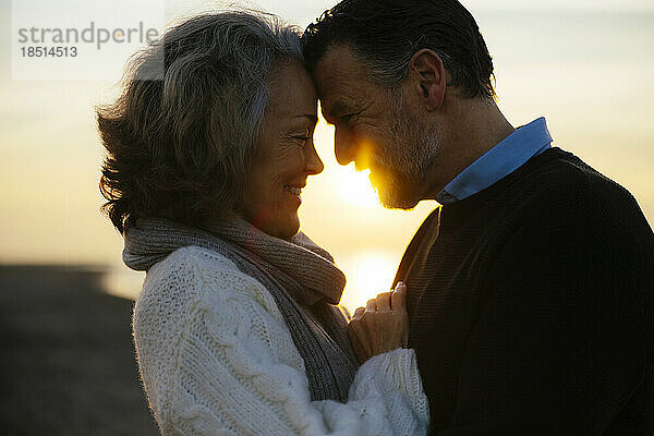 Lächelnde Frau umarmt Mann bei Sonnenaufgang