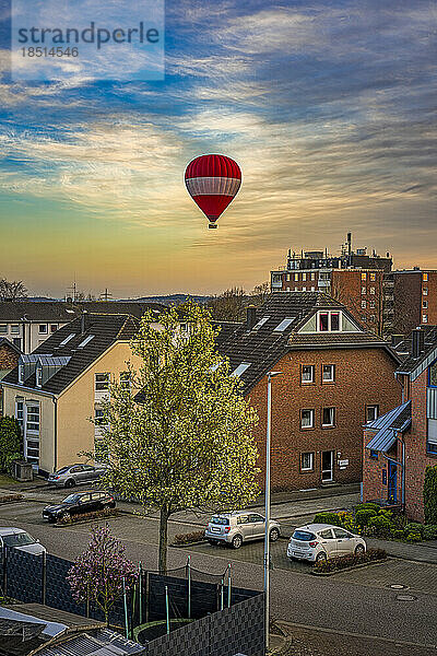 Deutschland  Nordrhein-Westfalen  Grevenbroich  Wohnviertel in der Abenddämmerung mit fliegendem Heißluftballon im Hintergrund