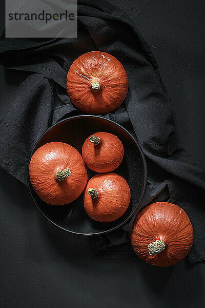Studio shot of bowl of pumpkins lying against black background
