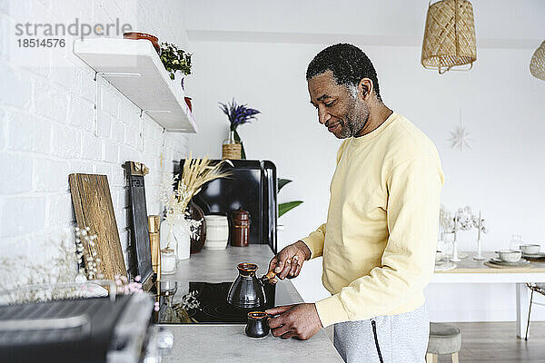 Reifer Mann bereitet zu Hause in der Küche Kaffee zu