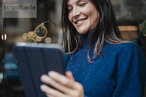 Glückliche Geschäftsfrau mit Tablet-PC und Brille